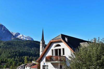 House and trees against clear blue sky