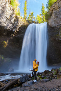 Rear view of man standing against waterfall