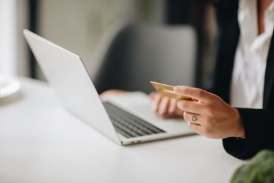 Midsection of businesswoman using mobile phone while holding credit card