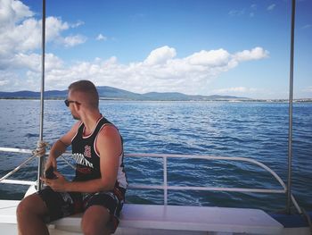 Full length of man sitting on sea against sky