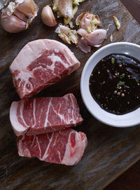 High angle view of raw beef with soy sauce in bowl on cutting board