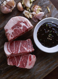 High angle view of raw beef with soy sauce in bowl on cutting board