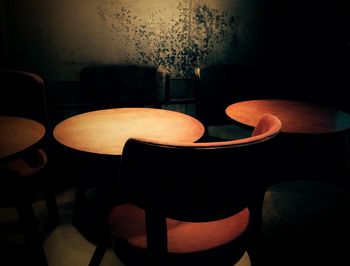 Empty chairs and tables in illuminated cafe