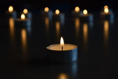 Close-up of illuminated candles on table in darkroom