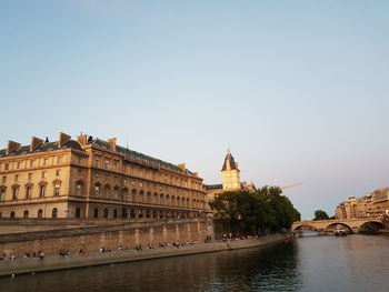 View of buildings by river against clear sky