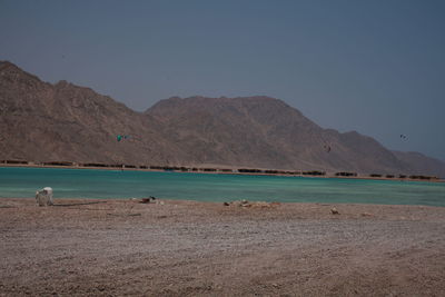 Scenic view of sea and mountains against clear blue sky