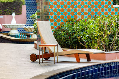 Empty chairs and tables in swimming pool against building