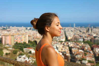 Close-up of young woman against buildings in city