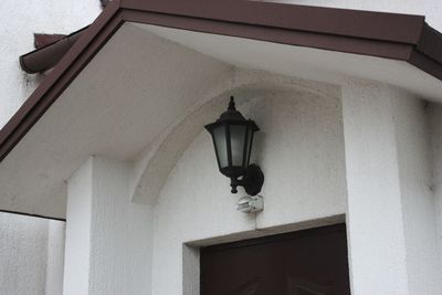 Low angle view of illuminated lamp hanging on building