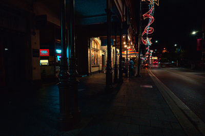 Illuminated street amidst buildings in city at night