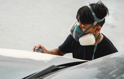 Mechanic wearing mask working on car at garage