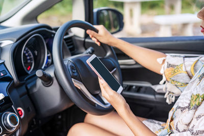 Midsection of man using mobile phone in car