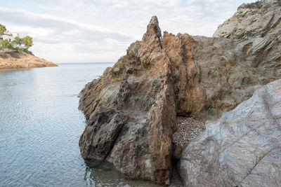 Rock formation by sea against sky