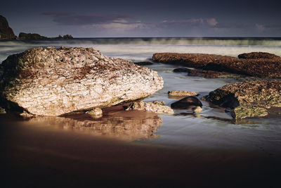 Rocks on sea shore against sky