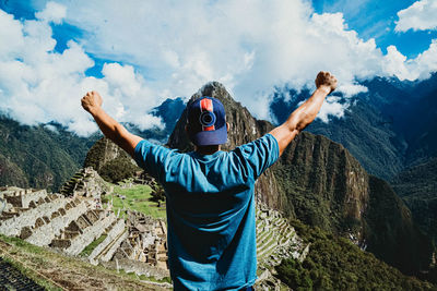 Rear view of person standing on mountain against sky