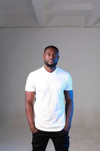 Portrait of young man standing against wall