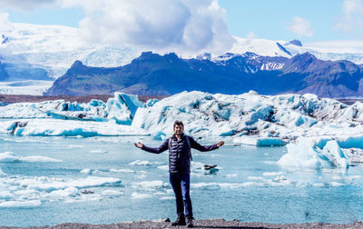 Full length of man with arms outstretched while standing against glacier
