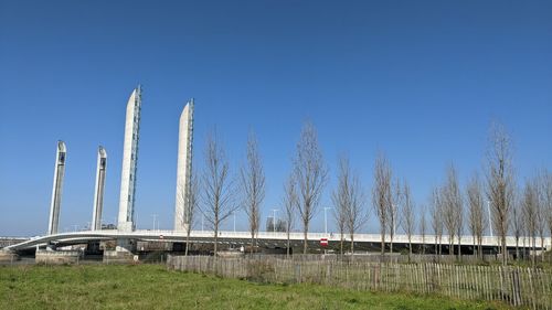 Panoramic shot of bridge on field against clear blue sky