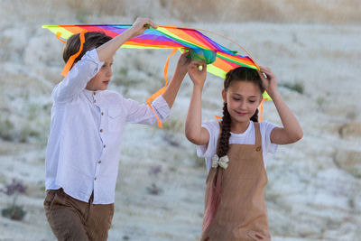 Children go sheltered from the rain with a kite.