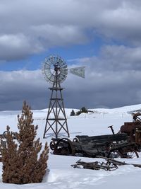 Electricity pylon on snow covered field against sky