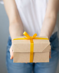 Close-up of hand holding yellow flower in box