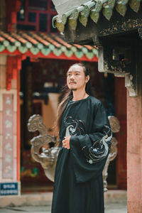Portrait of young woman standing against temple