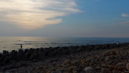 Scenic view of beach against cloudy sky