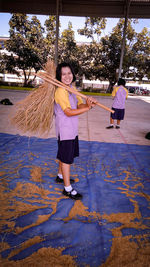 Full length portrait of a smiling woman holding umbrella