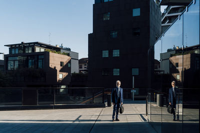 Senior businessman standing outside office building on sunny day