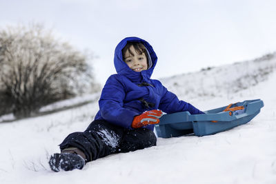 Portrait of smiling boy sitting on snow