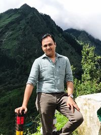 Portrait of smiling man standing on mountain against sky