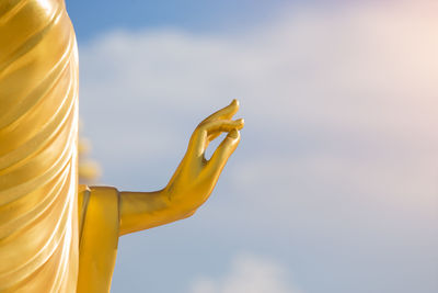 Close-up of yellow cross against sky