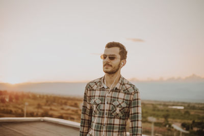 Man standing on terrace against sky during sunset