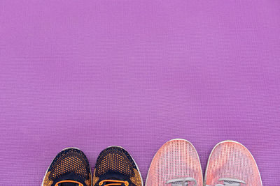 Low section of man standing on pink shoes