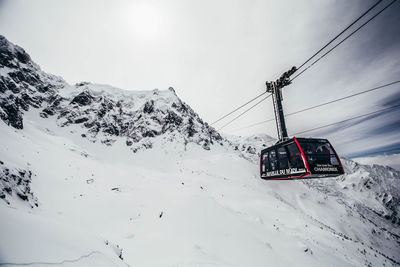 Overhead cable car on snow covered mountain against sky