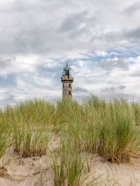 Lighthouse on beach against sky