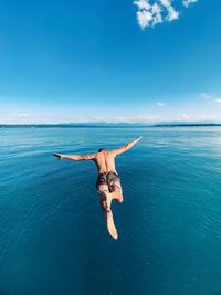 Full length of shirtless man diving into sea