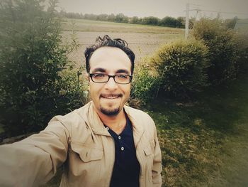 Portrait of smiling young man standing against plants