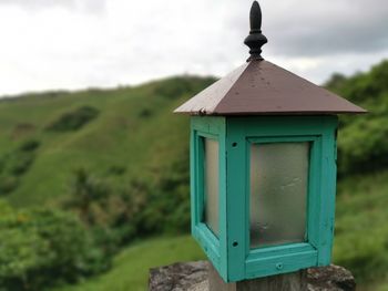 Close-up of birdhouse on field against sky