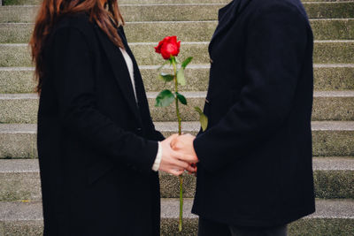 Midsection of couple holding hands standing outdoors