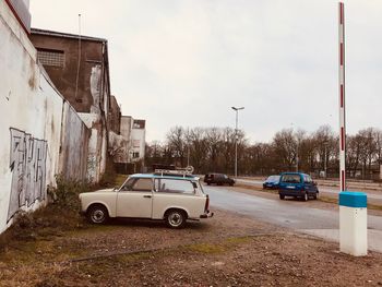 Cars on road by buildings against sky