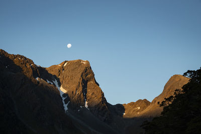 Low angle view of rocky mountains against clear blue sky