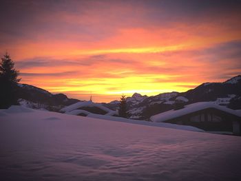 Scenic view of snow covered mountains against orange sky