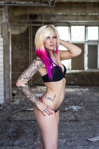 Side view of young woman wearing bikini standing in abandoned building