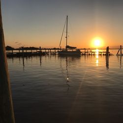 Silhouette boats in sea against sky during sunset