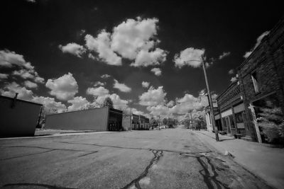 Empty road amidst buildings against sky