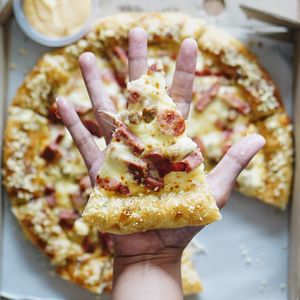 Cropped image of hand holding pizza piece