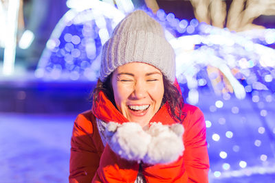 Smiling young woman in hat during winter at night