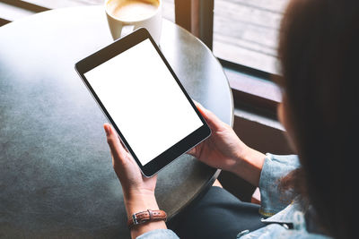 High angle view of woman using blank phone at table in cafe