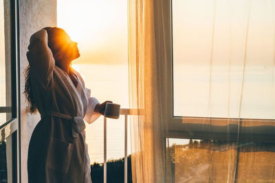 Rear view of woman standing against window